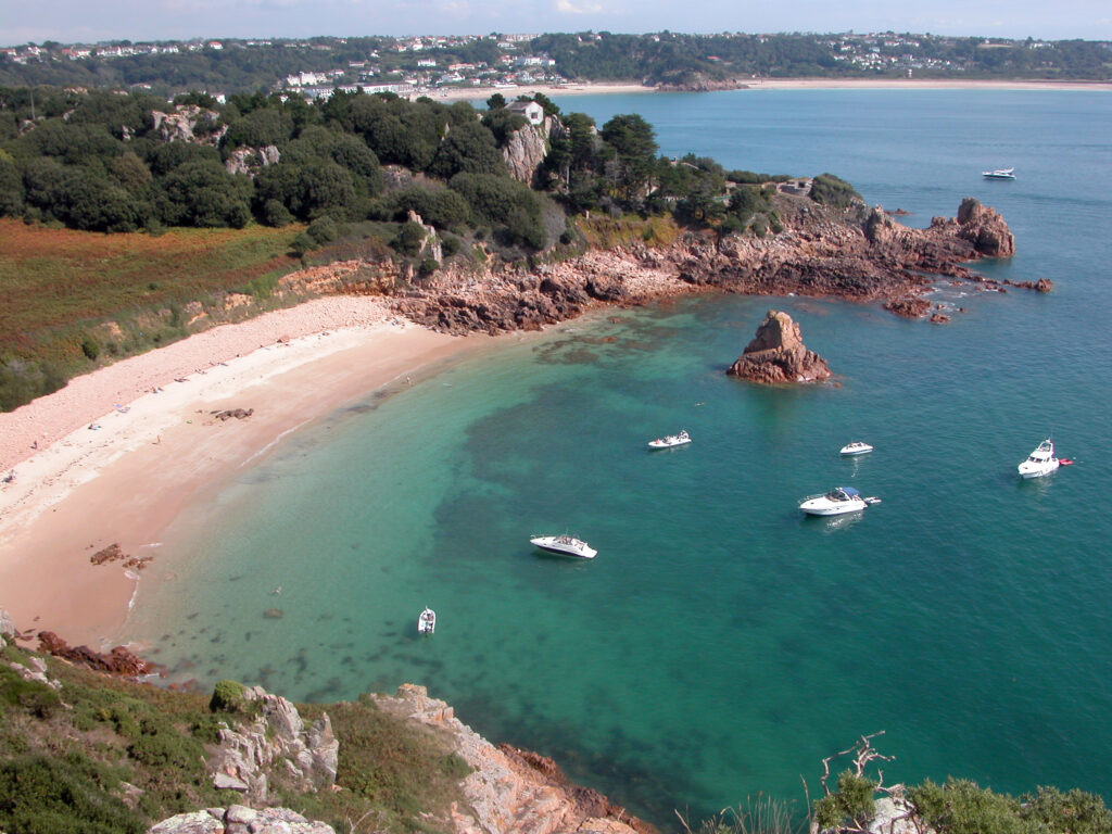 Ariel photograph of teal sea with 4 white boats in the water.